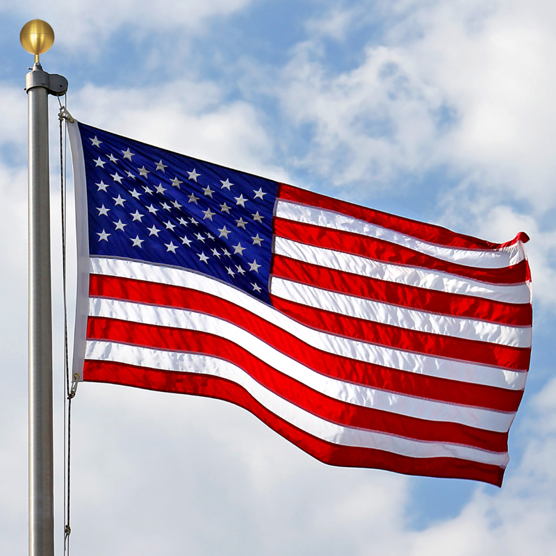 American flag waving against a blue sky with clouds