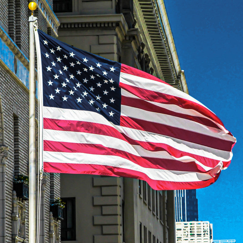 American flag waving in front of a building with a clear blue sky